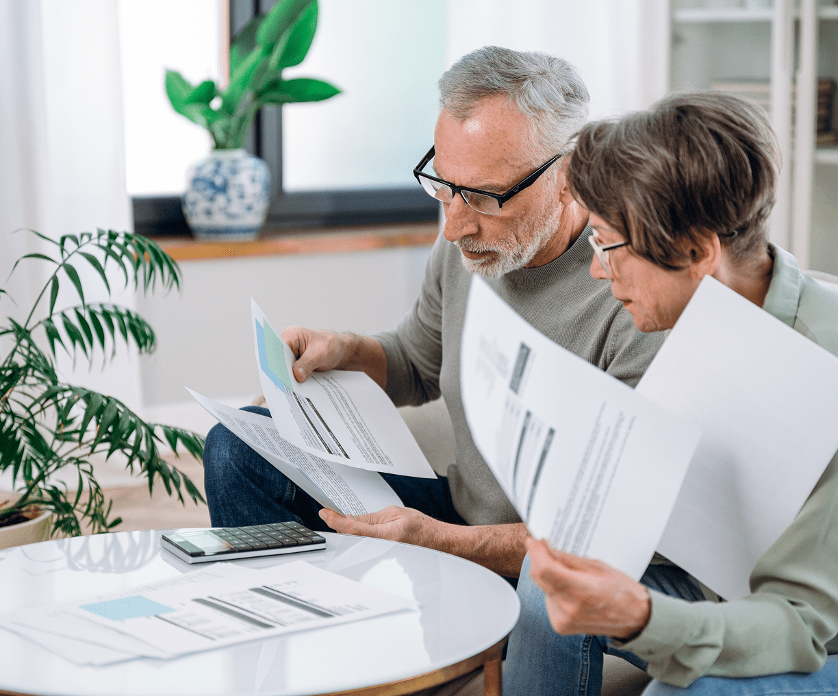 Elderly pair analyzing documents with calculator